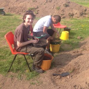 Student archaeologists Bethan and Simon sieving in the sun